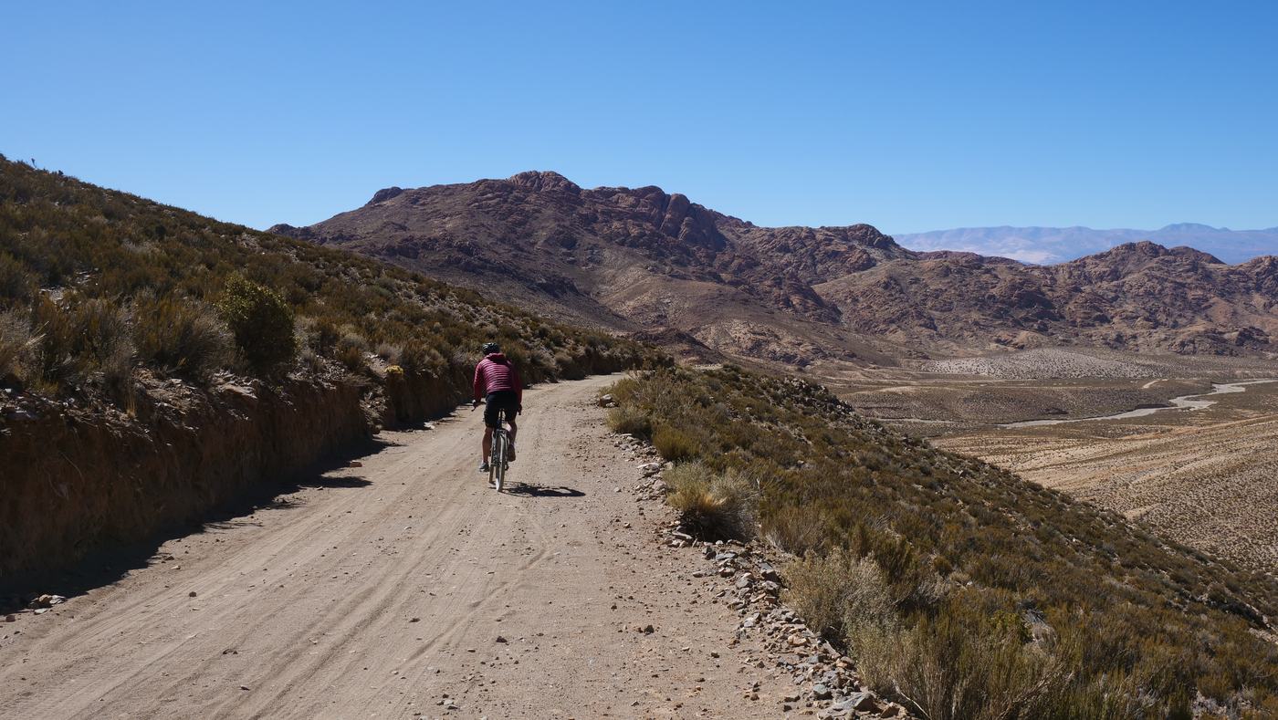 A rider climbing a dirt road above a high valley in northern Argentina