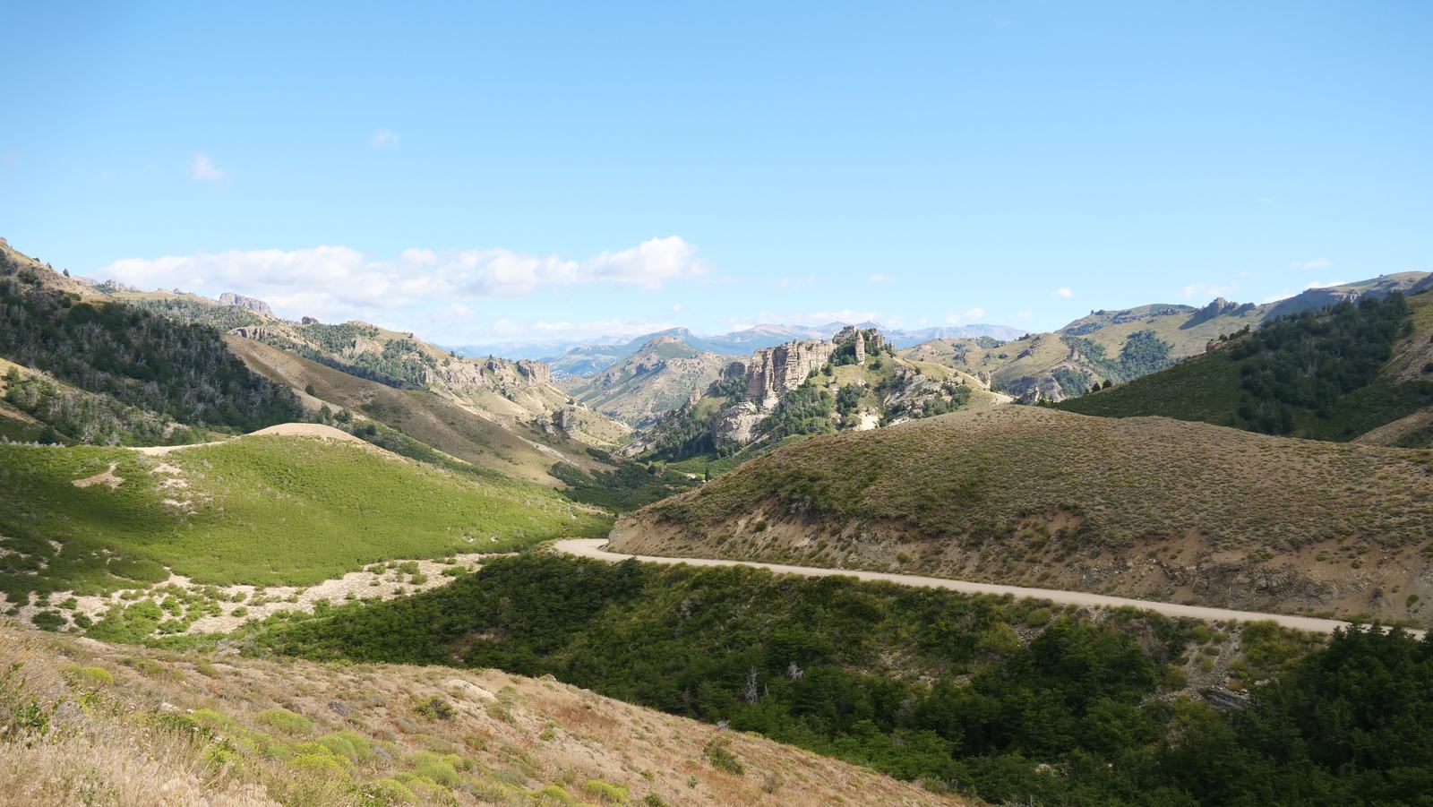 A gravel road winding through a green Patagonian valley